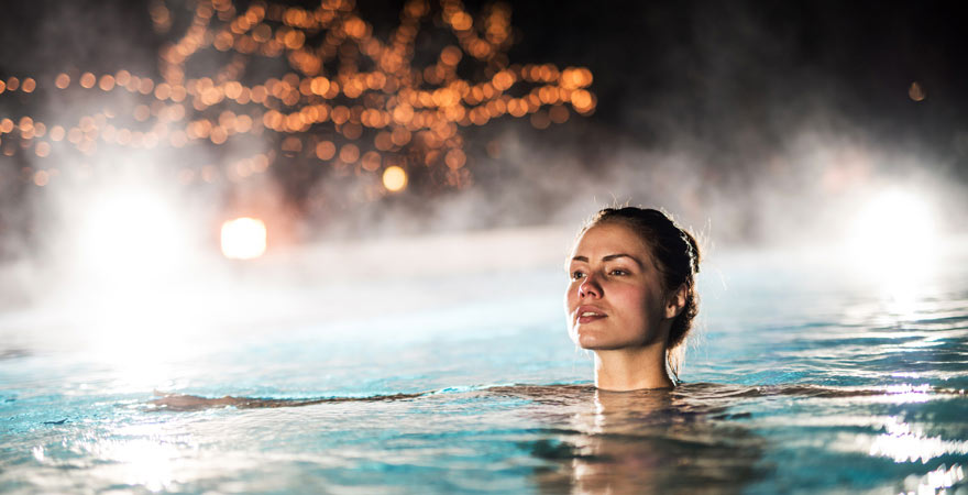 Frau schwimmt im beheizten Pool einer Therme