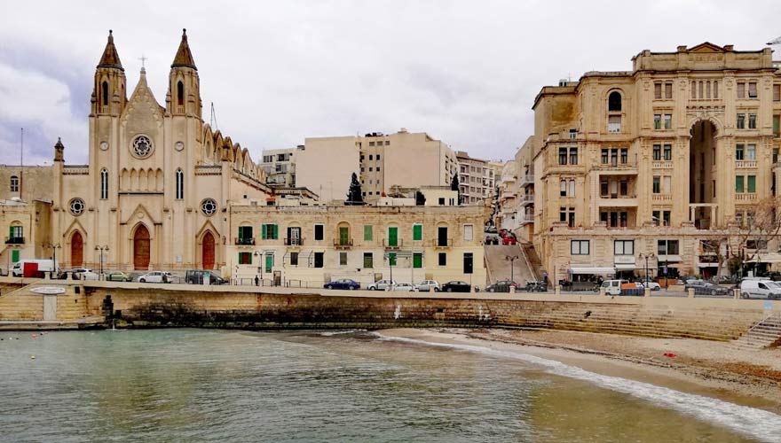 Schmaler Kieselstrand von der Balluta Bay vor der Kulisse von St. Julian's auf Malta