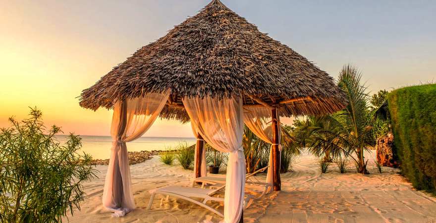 Pavillon mit dach aus Palmblättern im Abendlicht am Strand von Sansibar