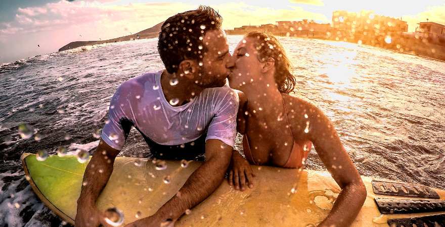 Ein küssendes Pärchen schwimmt auf einem Surfbrett im Meer