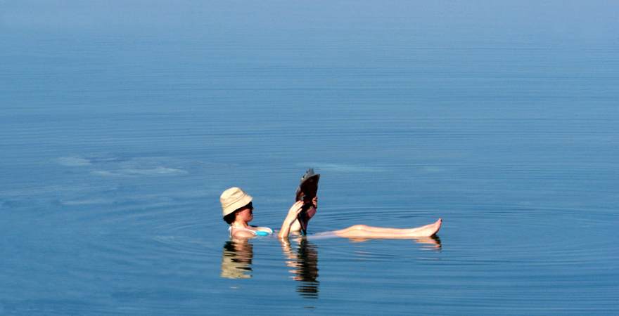 Eine Frau schwimmt im Toten Meer in Israel und liest dabei Zeitung
