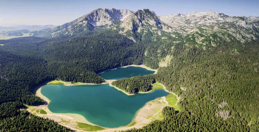 Ein dunkler Bergsee mit Gipfeln im Hintergrund