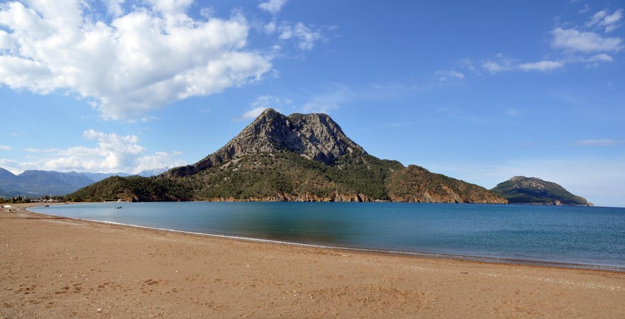 Der Sand-Strand Adrasan in der Türkei mit Blick auf das blaue Meer und einen grünen Hügel
