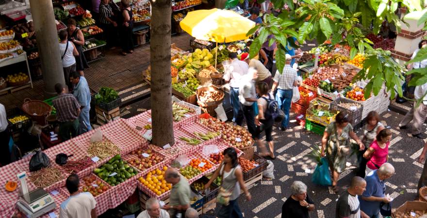 Einheimische und Touristen spazieren über denMarkt von Funchal auf Madeira auf dem Obst, Gemüse und Blumen angeboten ewrden