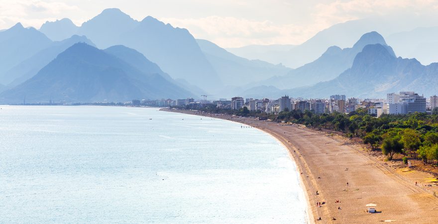 Der Konyaalti Strand in der Türkei mit Blick auf das Meer, Kiesstrand mit Sand, Wald und Bergen