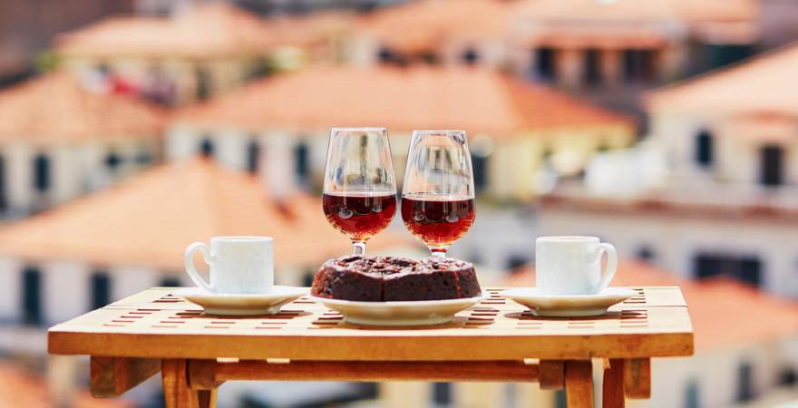Zwei Gläser mit Madeira Wein, Kaffee und der Honigkuchen Bolo de Miel mit Funchal Hauptstadt von Madeira im Hintergrund