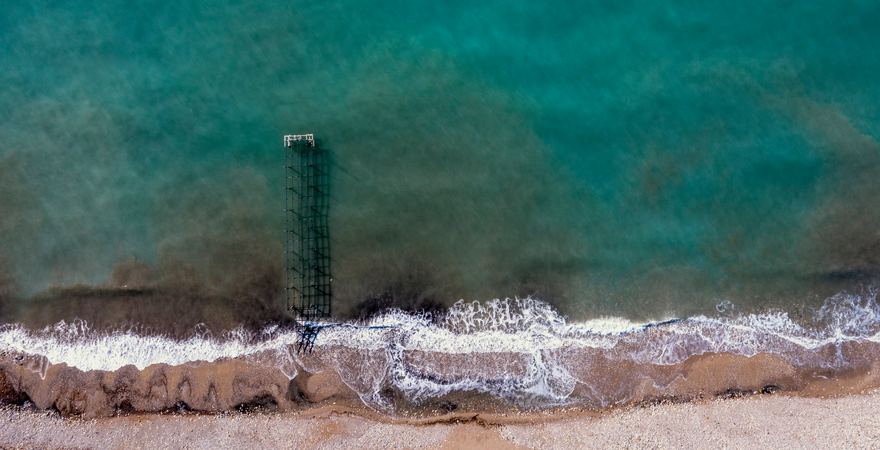 Ein Pier vor dem Lara Strand in der Türkei in Antalya mit Sand und Kies der ins Meer hineinragt und von Wellen umspült wird