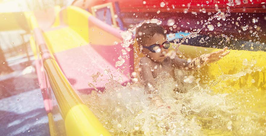 Little boy having fun sliding in water park