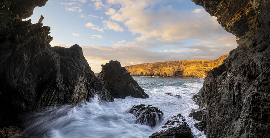 Die Höhlen von Ajuy an der Küste Fuerteventuras, unter einem blauen Himmel und über dem azurblauen Wasser der Kanarischen Inseln