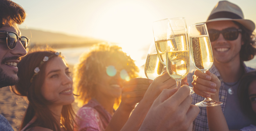 Freunde stoßen mit Sekt am Strand an