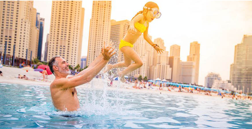 Vater mit Tochter beim Badespaß an einem Strand in Dubai