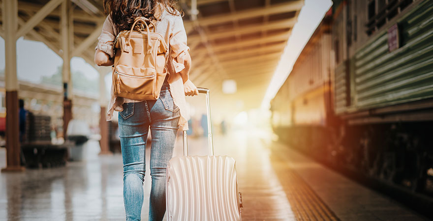 Frau mit Koffer am Bahnsteig