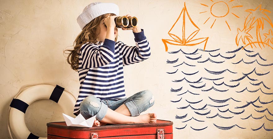 Kind als Matrose auf einem Koffer