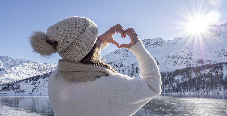 Frau formt ein Herz mit der Hand im Winter