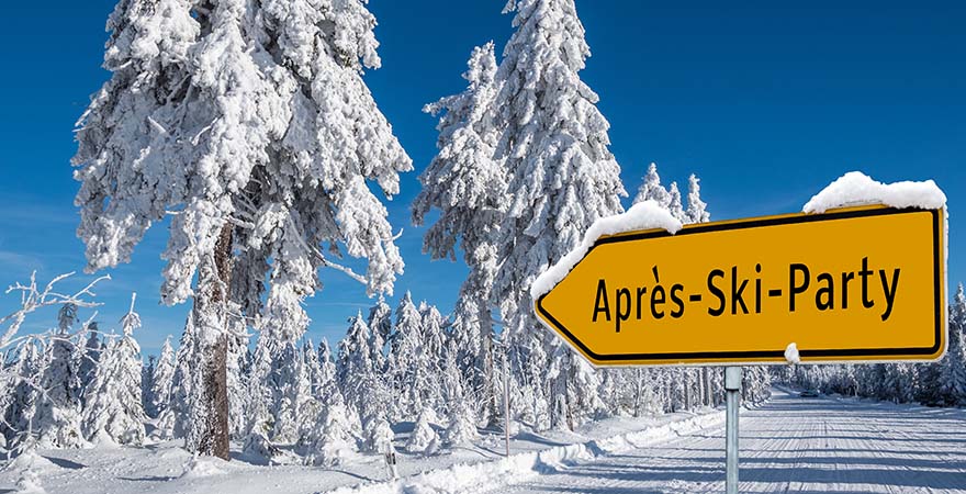 verschneite Bäume mit Wegweiser zur Après-Ski-Party