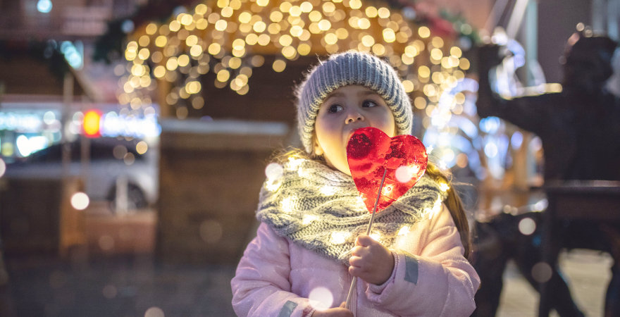 Kind auf einem Weihnachtsmarkt mit Lolli