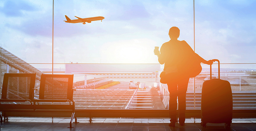 Person die mit Koffer am Flughafen wartet