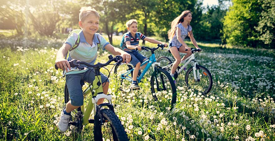 3 Kinder auf Fahrrädern auf der Wiese