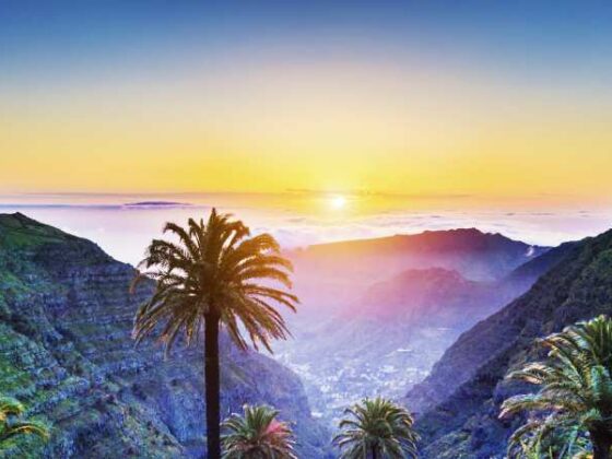 Tropische Landschaft mit Palmen und Bergen bei Sonnenuntergang an Atlantik-Küste auf Teneriffa