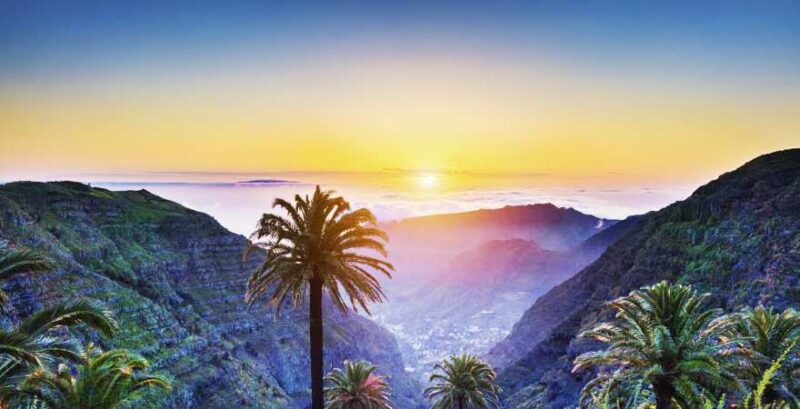 Tropische Landschaft mit Palmen und Bergen bei Sonnenuntergang an Atlantik-Küste auf Teneriffa
