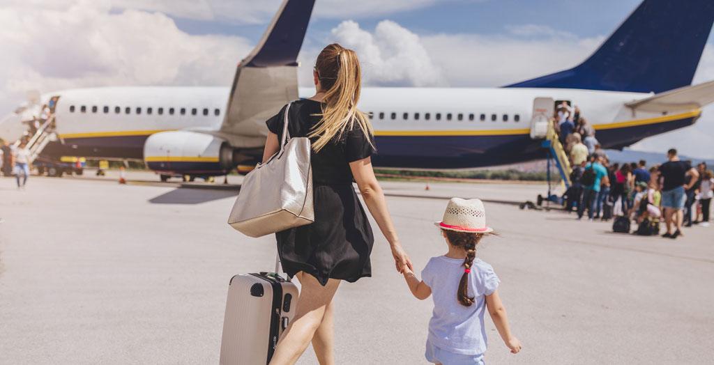 Junge Mutter und ihre schöne Tochter steigen in ein Flugzeug.