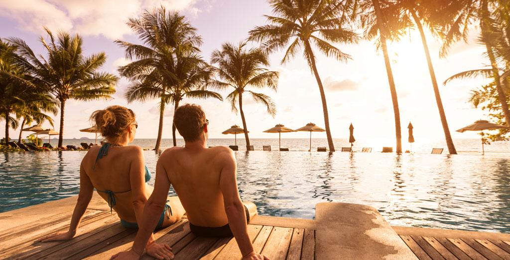 Paar entspannt am Pool zum Sonnenuntergang