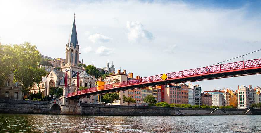 St-Georges-Kirche an der Saône im französischen Lyon mit einer roten Brücke im Vordergrund