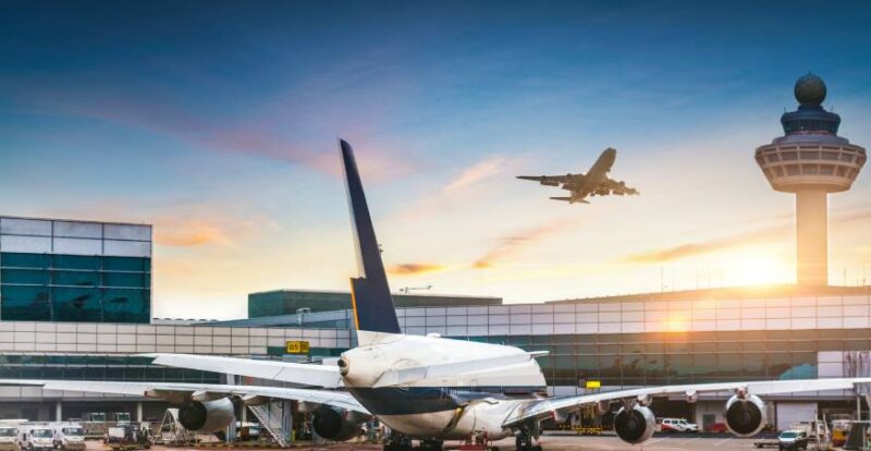 Flughafen mit Flugzeug am Boden und startendem Flugzeug in der Luft