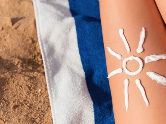 Aus Sonnencreme gemachte Sonne auf Bein am Strand