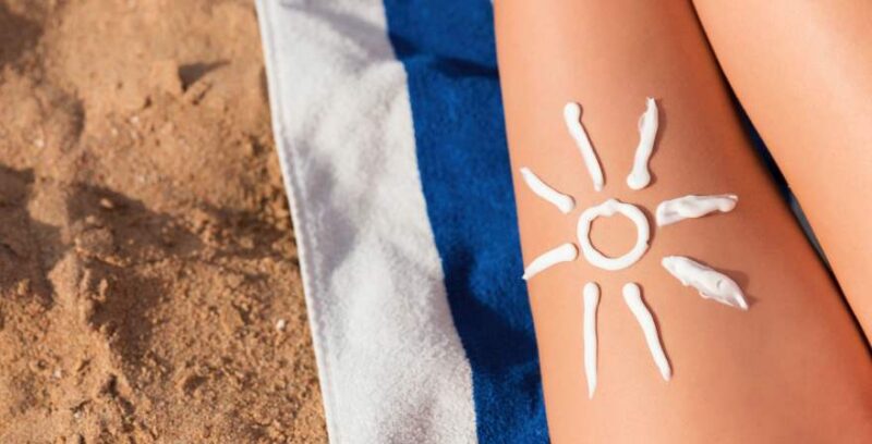 Aus Sonnencreme gemachte Sonne auf Bein am Strand