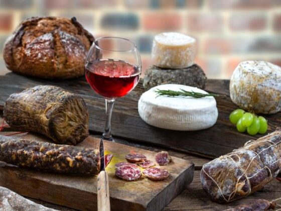 Wurst, Käse, Brot und Wein auf Holzbrett angerichtet