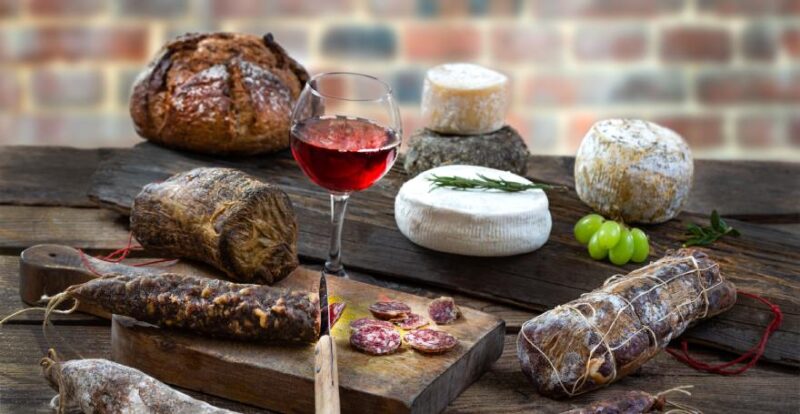 Wurst, Käse, Brot und Wein auf Holzbrett angerichtet