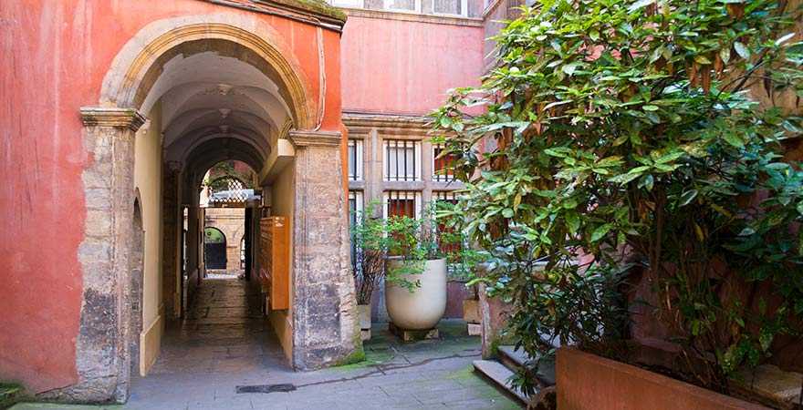 Traboule in Lyon: Innenhof eines roten Gebäudes mit Grünpflanzen