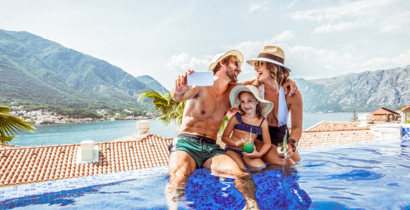 Familie genießt gemeinsame Zeit im Infinity-Pool mit malerischem Blick auf die Berge von Montenegro im Hintergrund