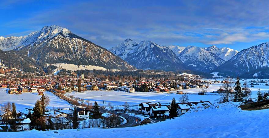 Blick über das verschneite Tal auf Oberstdorf und die Alpen