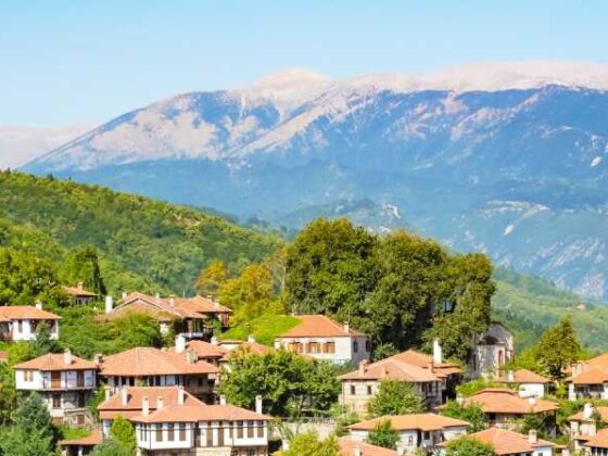 Olympische Riviera: Häuser an grünem Hügel mit Gebirge in Hintergrund