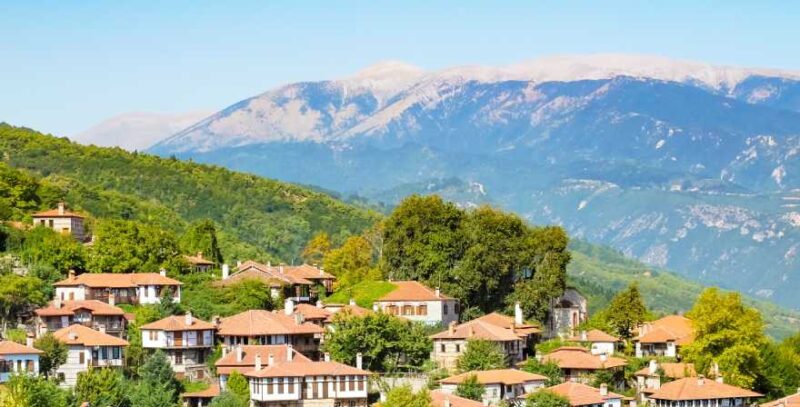 Olympische Riviera: Häuser an grünem Hügel mit Gebirge in Hintergrund