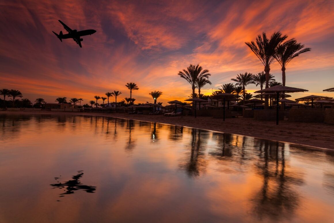 Äygpten Strand mit Palmen und Flugzeug im Sonnenuntergang