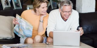 Fröhliches älteres Paar mit Kreditkarte vor Laptop