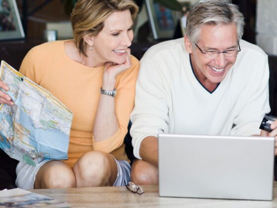 Fröhliches älteres Paar mit Kreditkarte vor Laptop