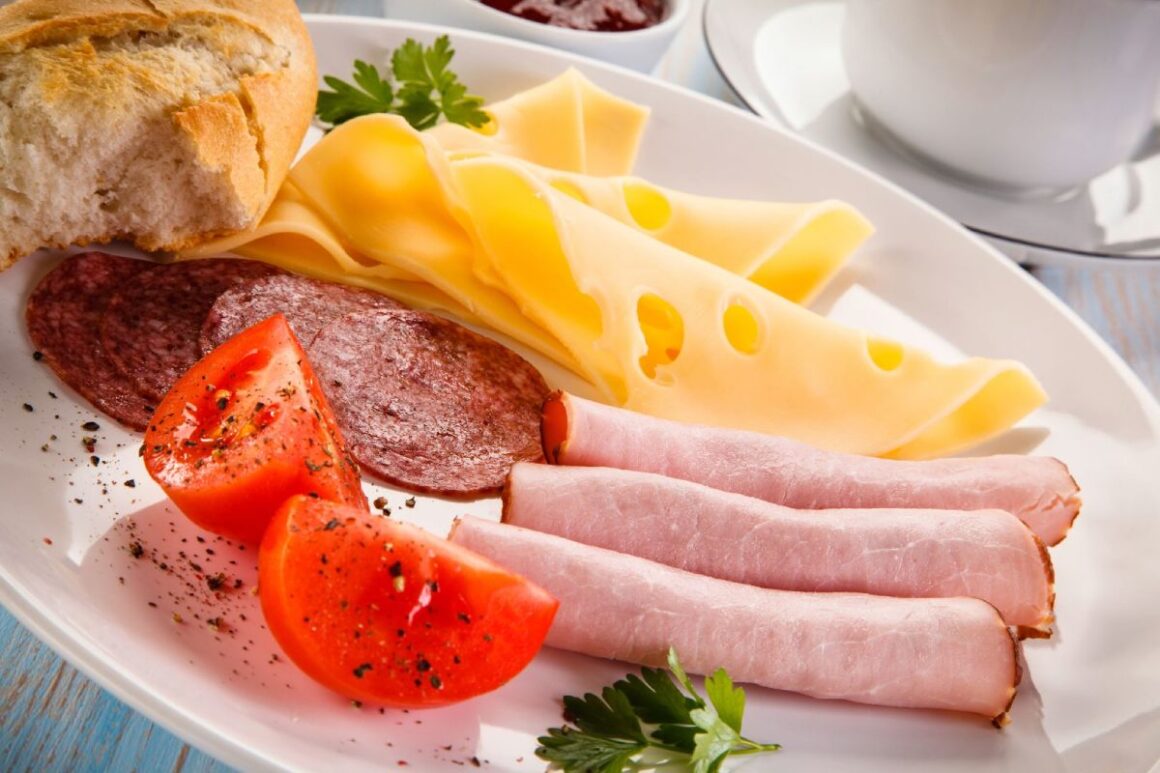 Nahaufnahme Frühstücksteller mit Wurst und Käse, Tomate und Brötchen