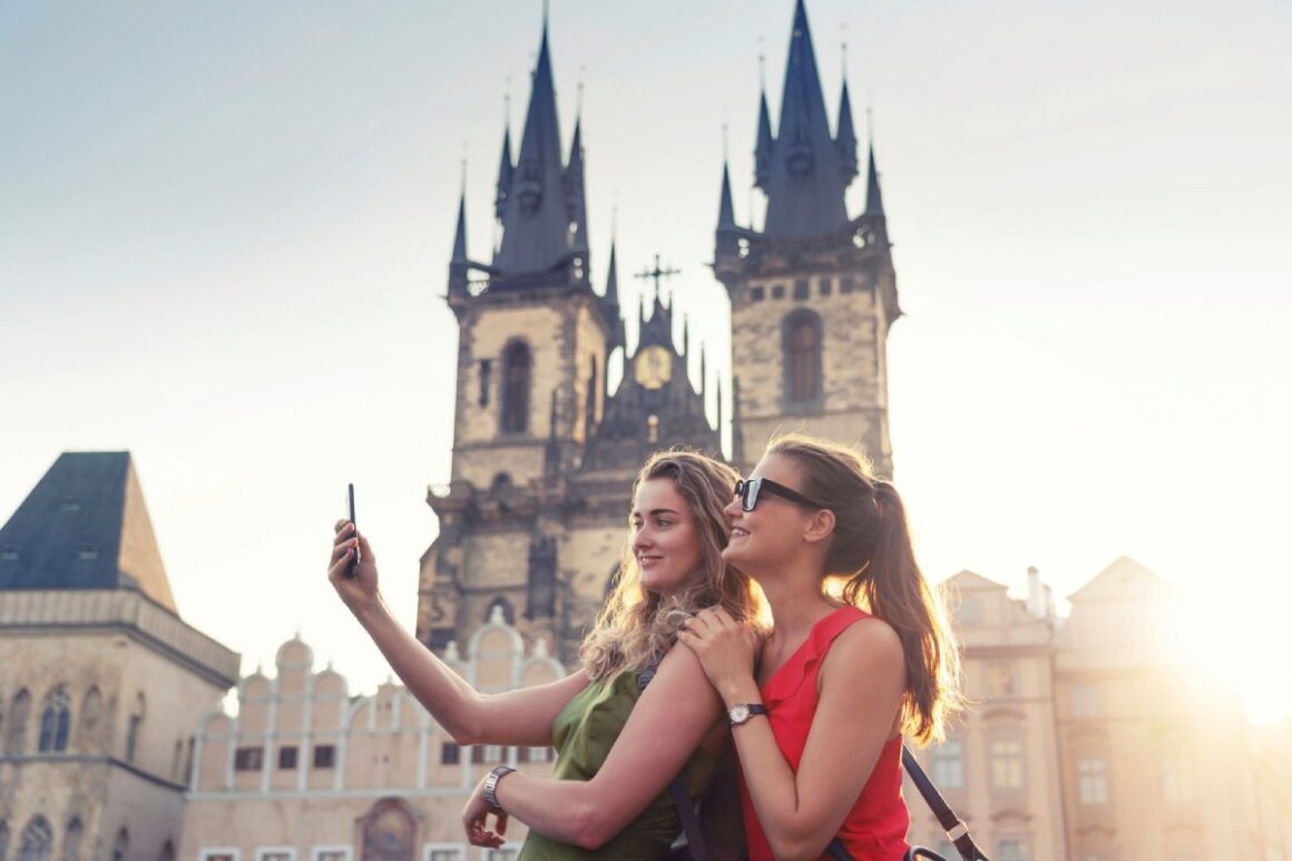 Zwei junge Touristinnen machen Selfie vor Kirche in Prag