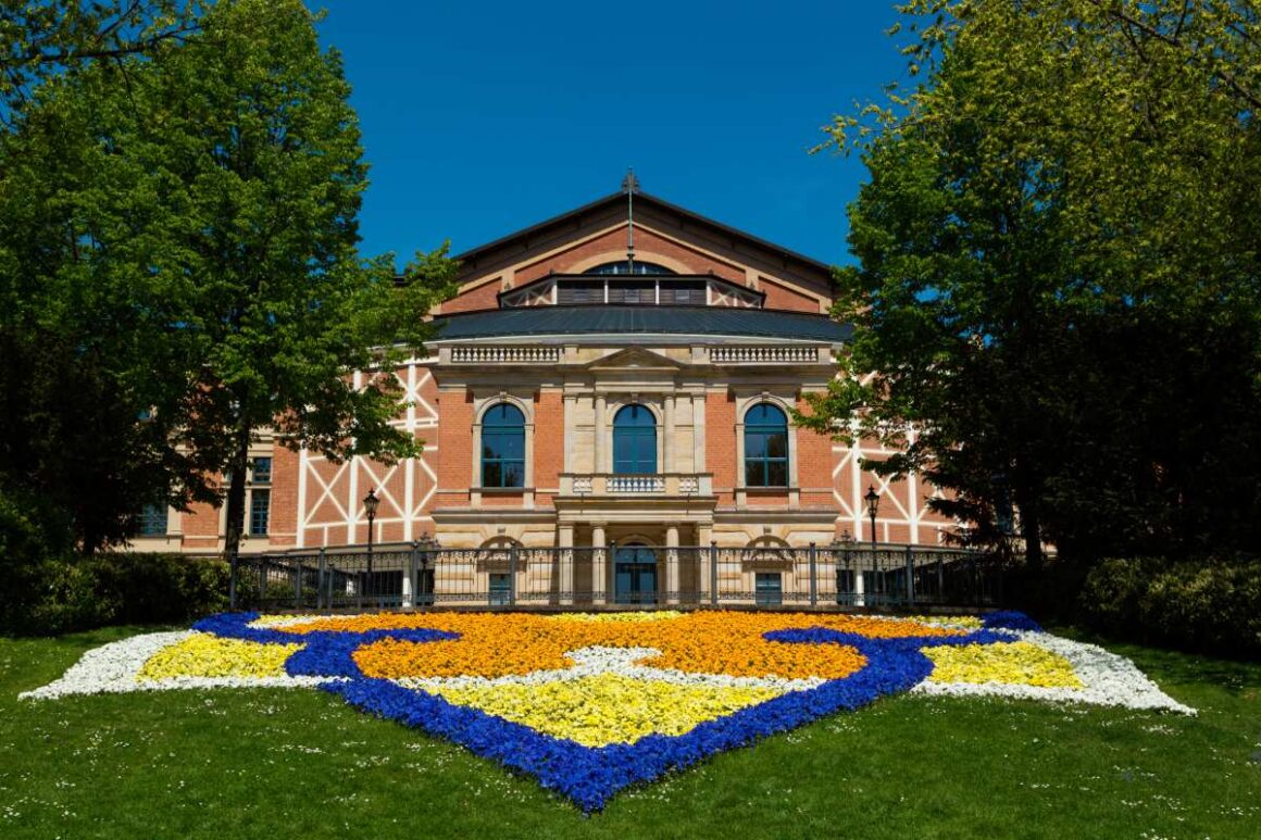 Bayreuther Festspielhaus auf dem grünen Hügel mit buntem Blumenbeet