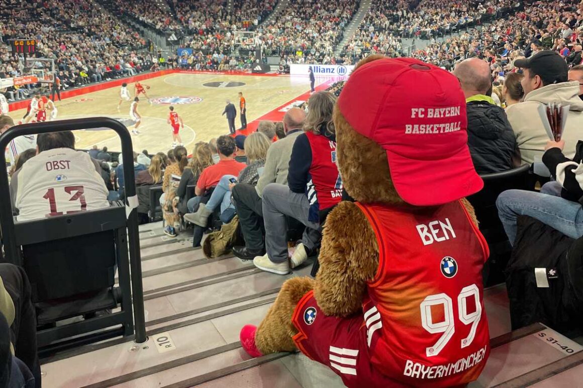 FC Bayern Basketball Maskottchen Ben in SAP Garden von Hinten auf Treppe sitzend in Richtung Spielfeld
