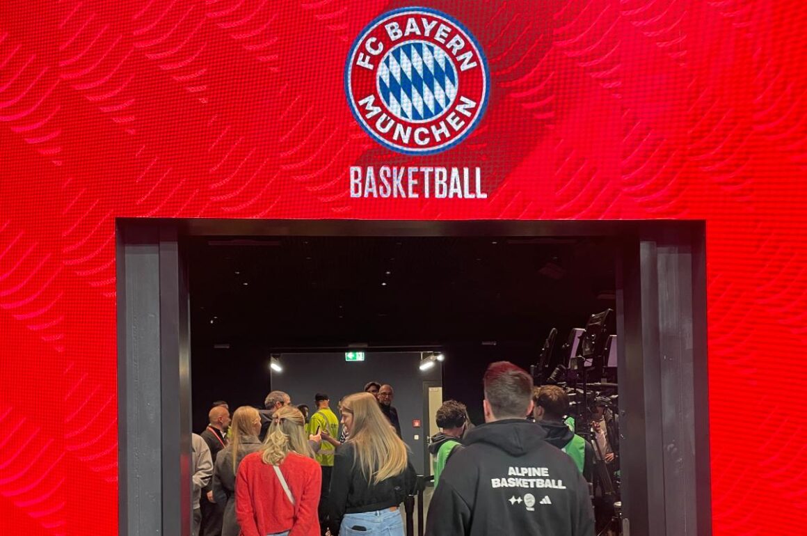 FC Bayern Basketball Logo über einen rot umrahmten Durchgang und sonnenklar.TV-Mitarbeiter