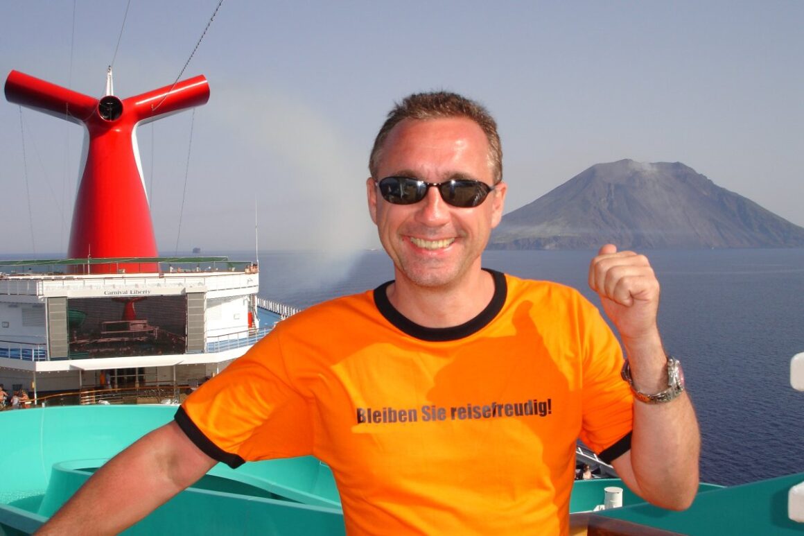 Ulf -Dieter Kunstmann an Bord eines Schiffs mit sonnenklar.TV-T-Shirt mit Berg in Hintergrund