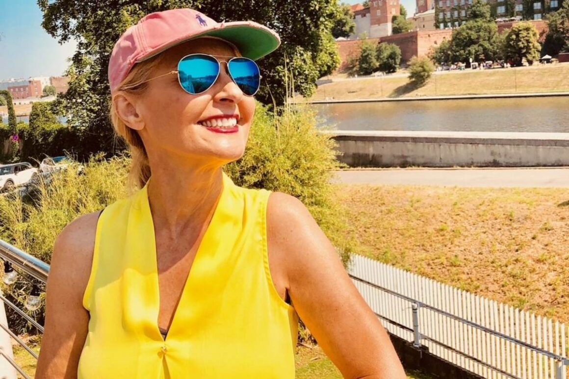 Chere Alice Zimmermann in gelber Bluse, Cap und Sonnenbrille