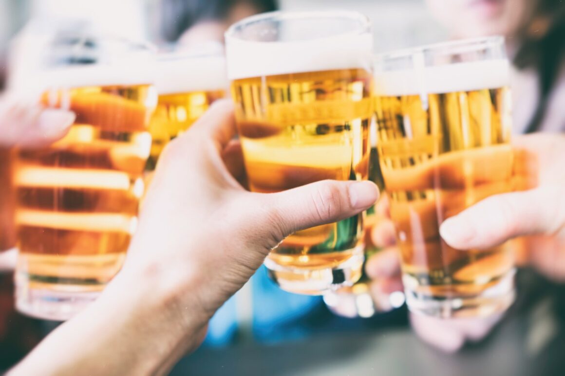 Nahaufnahme von Händen, die mit Bier anstoßen