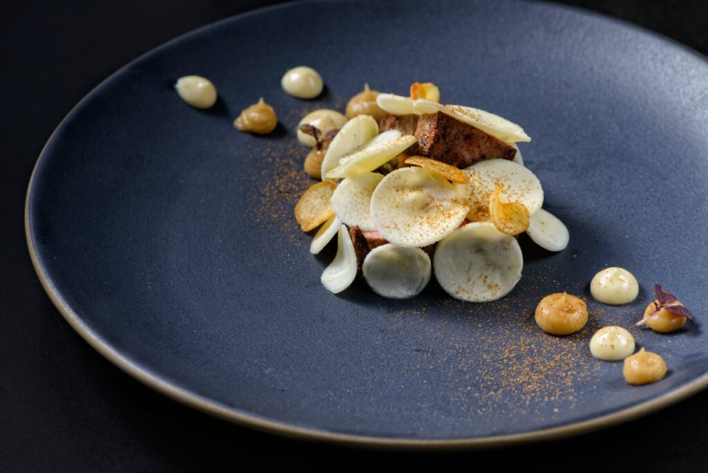 Grasrindfleisch mit Pastinaken in Nahaufnahme auf blauem Teller