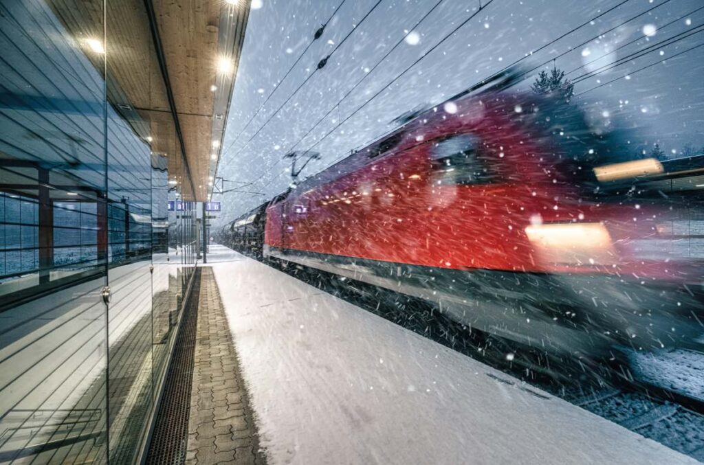 Fahrender Zug am Bahnsteig mit Schneefall